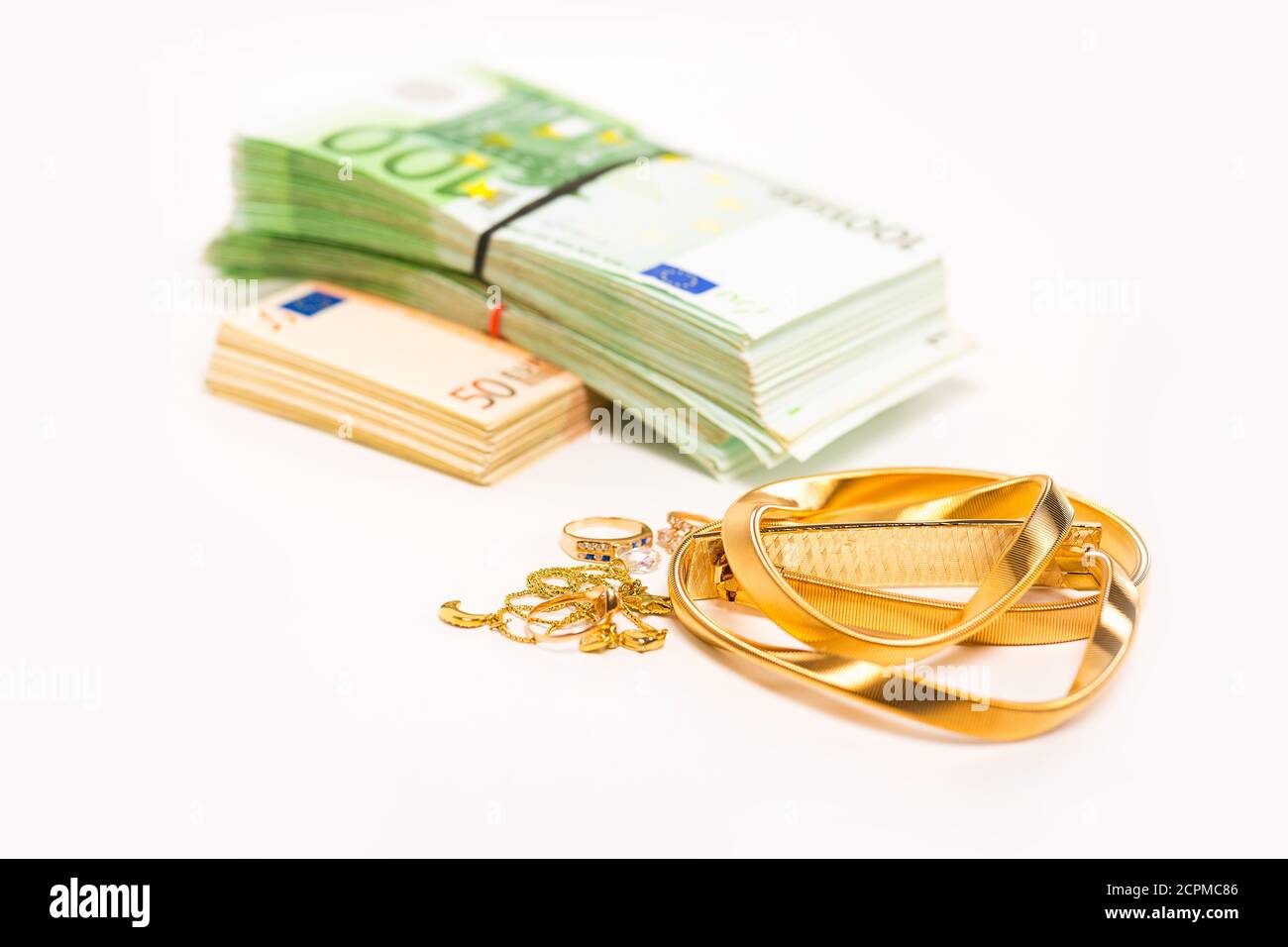 Bargeld für Goldschmuck liegt neben einem Haufen Euro-Banknoten Bargeld isoliert auf weißem Hintergrund. Cash-for-Gold-Geschäftskonzept Stockfoto
