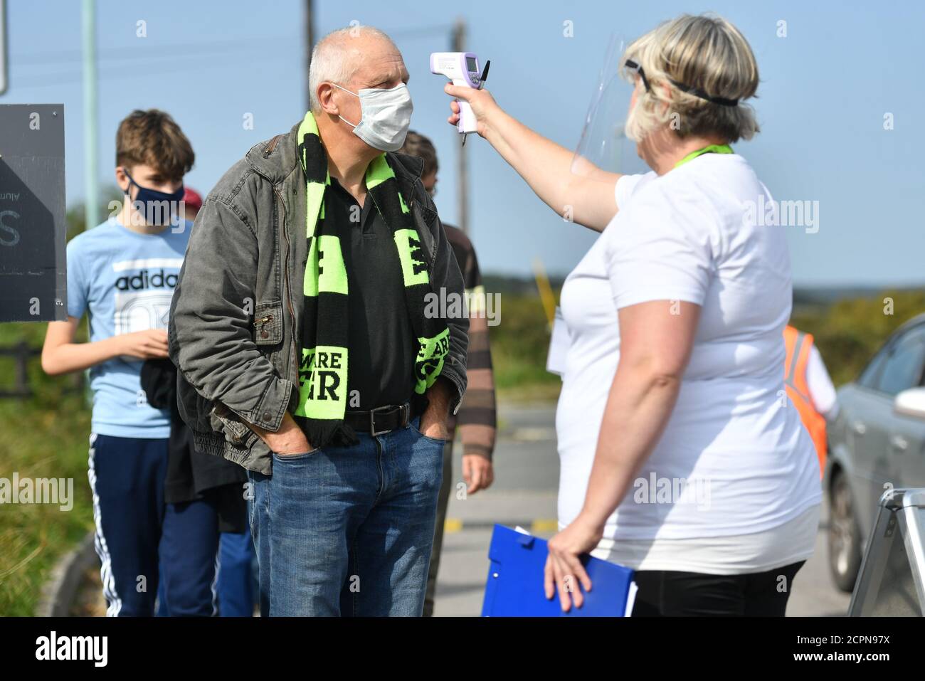 Ein Steward in PPE testet die Temperatur eines Fans während des Sky Bet League Two Spiels im New Lawn, Nailsworth. Stockfoto