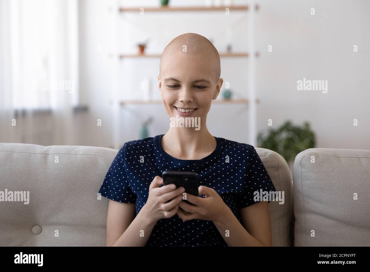 Lächelnde kranke haarlose Frau SMS auf Handy Stockfoto