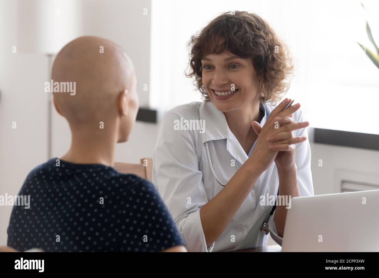 Lächelnde Krankenschwester und kranke haarlose Frau sprechen im Krankenhaus Stockfoto