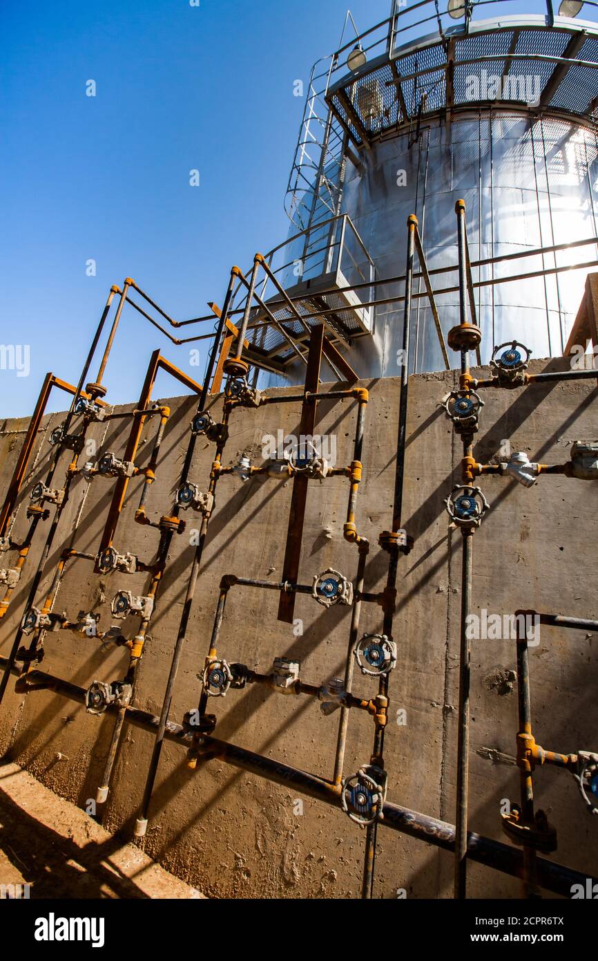 Schwefelsäureanlage. Rohre, Ventile und Schwefel Ofen auf Betonwand auf blauem Himmel Hintergrund. Stockfoto