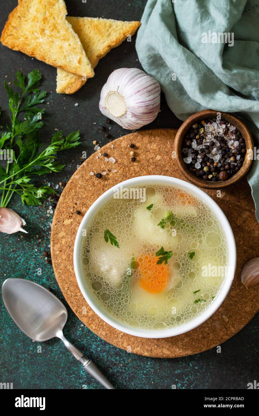 Hühnersuppe mit Gemüse auf einer Tischplatte aus dunklem Stein. Draufsicht flach lagen Hintergrund. Stockfoto