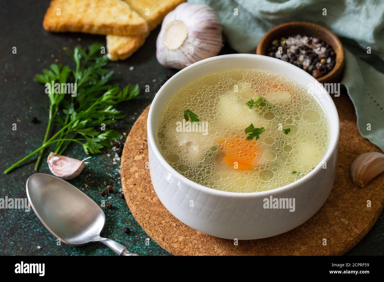 Hühnersuppe mit Gemüse auf einer Tischplatte aus dunklem Stein. Stockfoto