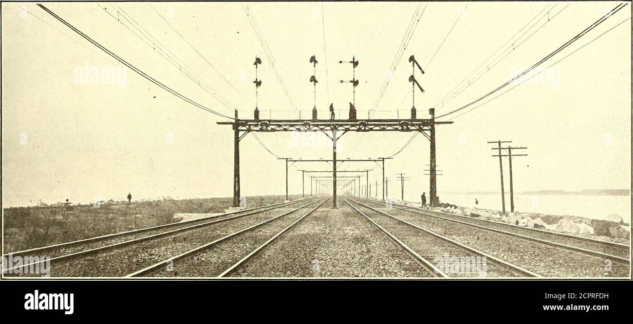. Elektrische Eisenbahn Zeitschrift . Abb. 14 – Southern Pacific 1200-Volt Lines – Oberleitungsbrücke Konstruktion auf einem vierspurigen Tangentialabschnitt gezogene Kupferlitzen mit hoher Spannung und vier Nals sowie alle Knotenpunkte und Kreuzungen sind durch No geschützt. 4 feste Phosphor-Bronze-Leiter, die alle elektrisch ineinandergreifende Anlagen sind, die von an allen drei Türmen verankerten Alter-Anchored betrieben werden. Am Turm Nr. 1 sind alle Kabel mit beiden Gleisschienen für die Stromkreise stromführende. go6 ELECTRIC RAILWAY JOURNAL. [Vol. XXXVIII, Nr. 17. Bis auf wenige Ausnahmen werden beide Gleise aller Gleise für beide Schilder verwendet Stockfoto