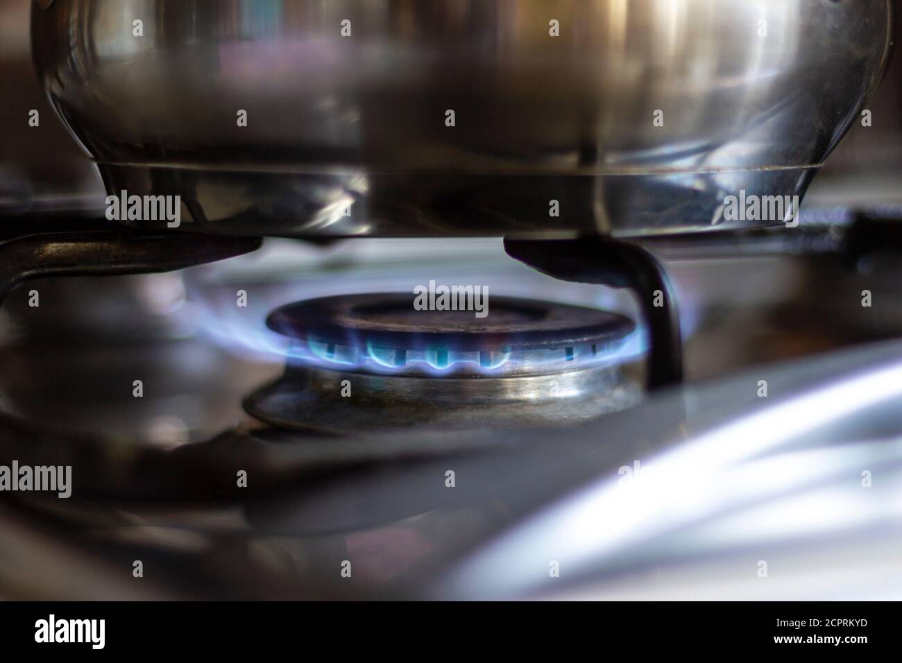 Nahaufnahme eines Edelstahltopfes, der auf einem Küchenherd mit Gasbrenner steht. Stockfoto