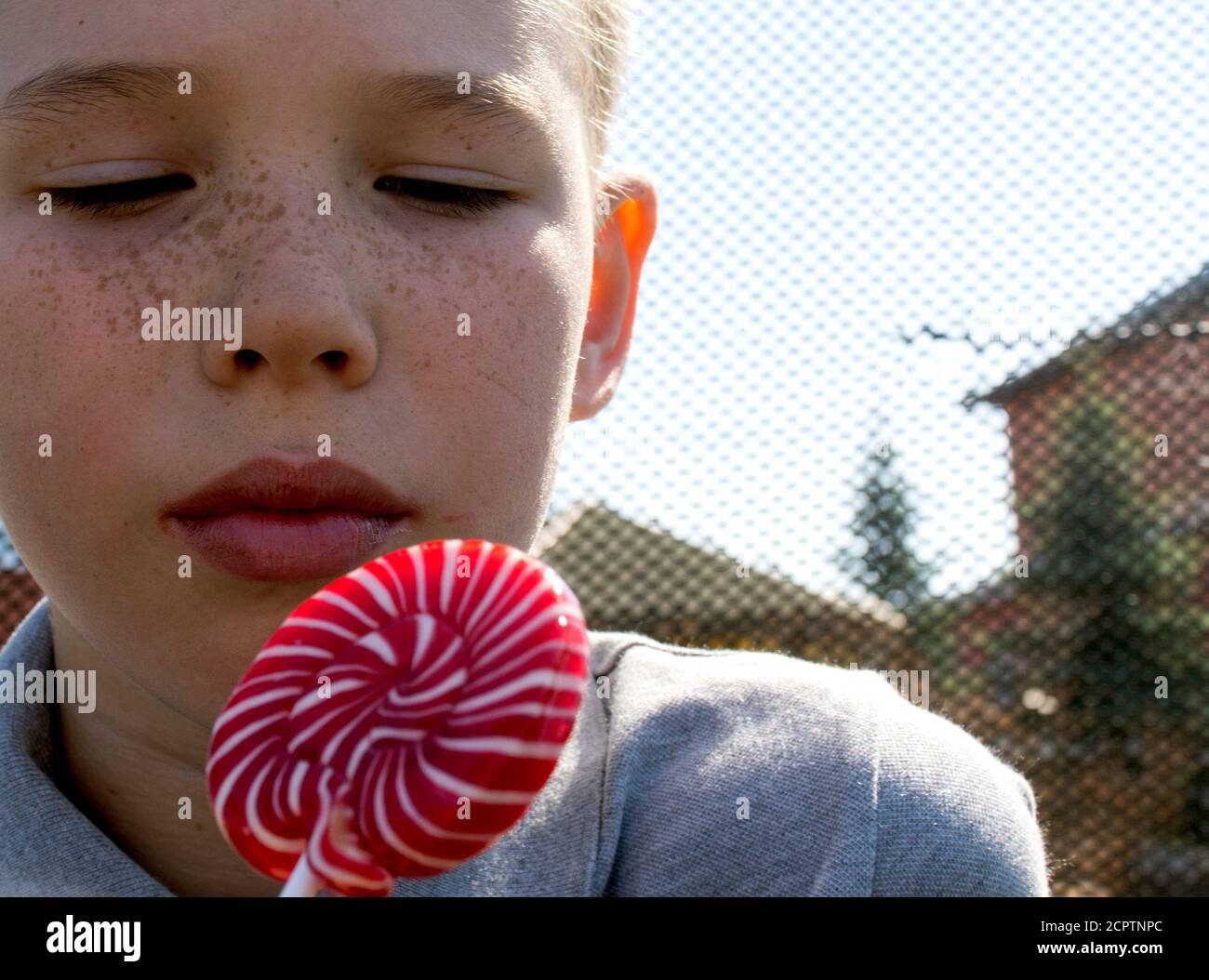 Der Junge isst einen leckeren Lollipop. Der Junge isst einen leckeren Lollipop. Der Junge leckt den Lutscher. Lollipop. Stockfoto