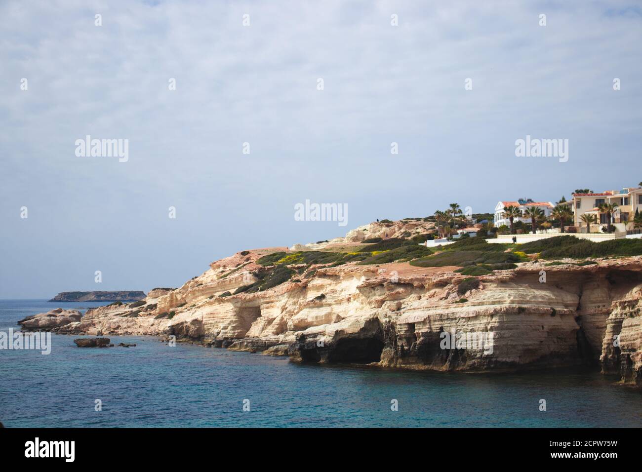 Zypern, Mittelmeer, Meereshöhlen, Rocky Coast mit einer Stadt darüber Stockfoto