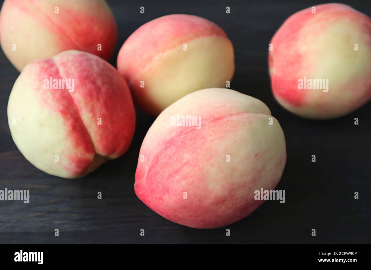 Nahaufnahme frisch reife Pfirsiche verstreut auf schwarzem Holztisch Stockfoto