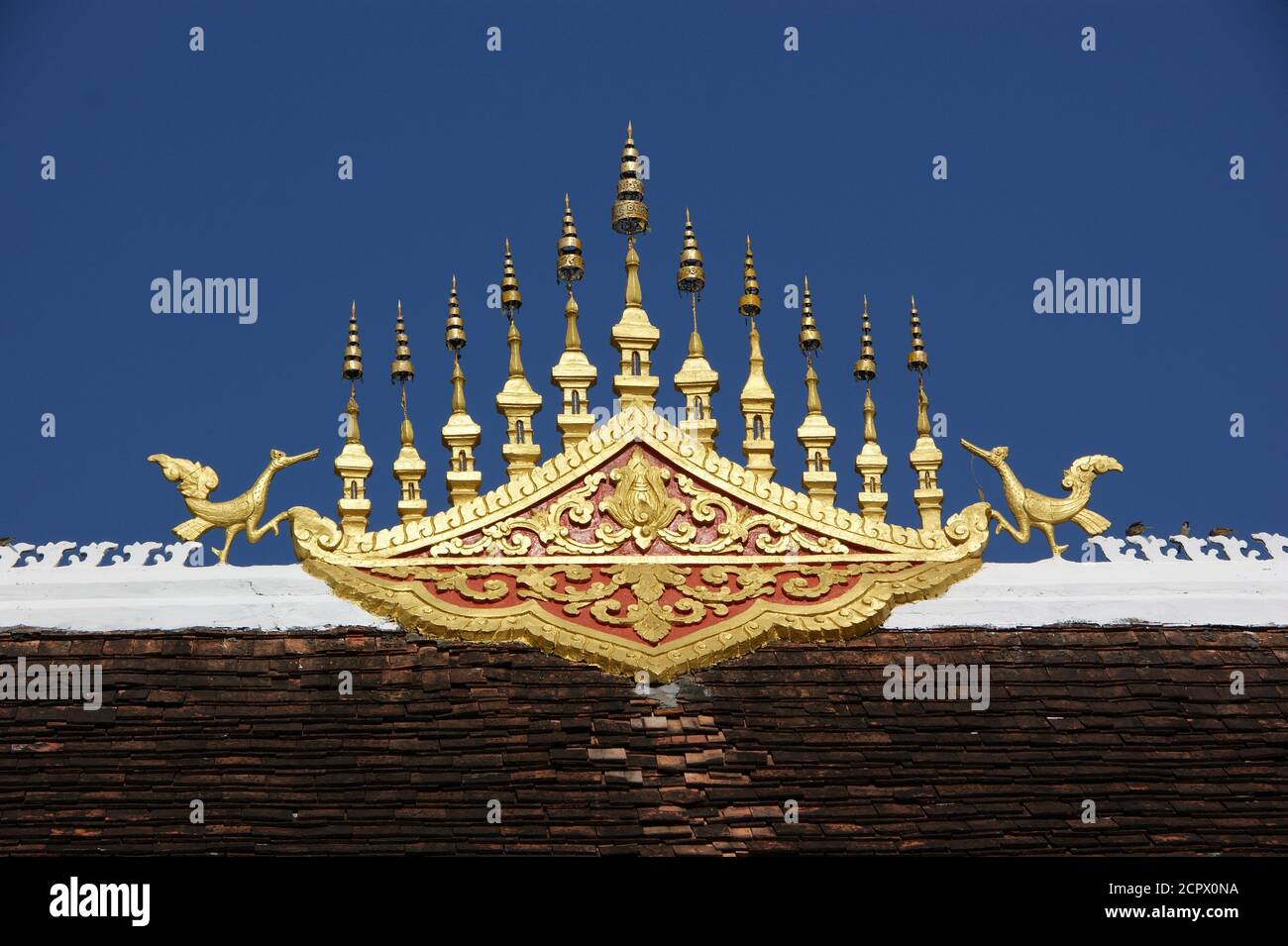 Zwei Chofa halten eine goldene Dachdekoration auf einem laotischen Tempel. Stockfoto