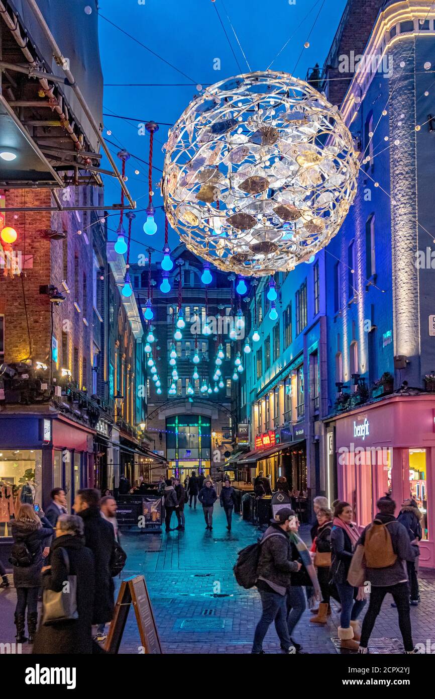 Menschenmassen, die zu Weihnachten entlang der Carnaby Street mit dem Ocean-Motto Carnaby Project Zero Christmas Lights Overhead, London, Großbritannien, spazieren Stockfoto