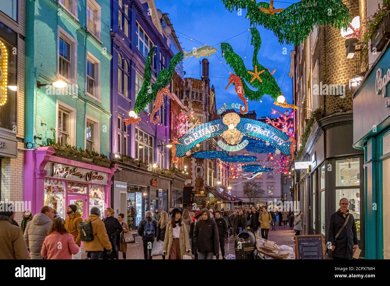 Menschenmassen, die zu Weihnachten entlang der Carnaby Street mit dem Ocean-Motto Carnaby Project Zero Christmas Lights Overhead, London, Großbritannien, spazieren Stockfoto