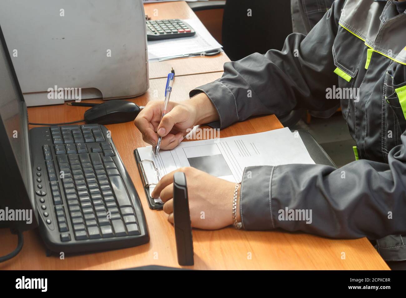 Der Meister füllt den Befehl auf dem Formular sitzend aus An der Rezeption Stockfoto