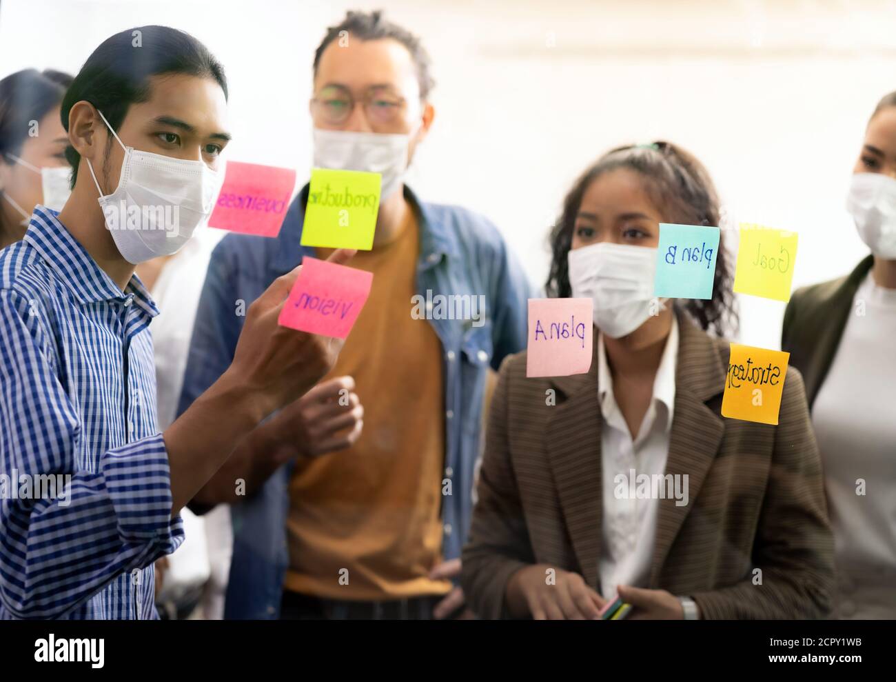 Interracial asiatische Business-Team Brainstorming Idee im Büro Besprechungsraum nach Wiedereröffnung wegen Coronavirus COVID-19 Stadt Lockdown. Sie tragen Gesichtsmaske Stockfoto