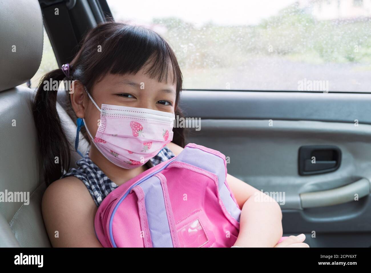 Asiatische kleine Kind Mädchen tragen Maske im Auto sitzen Stockfoto
