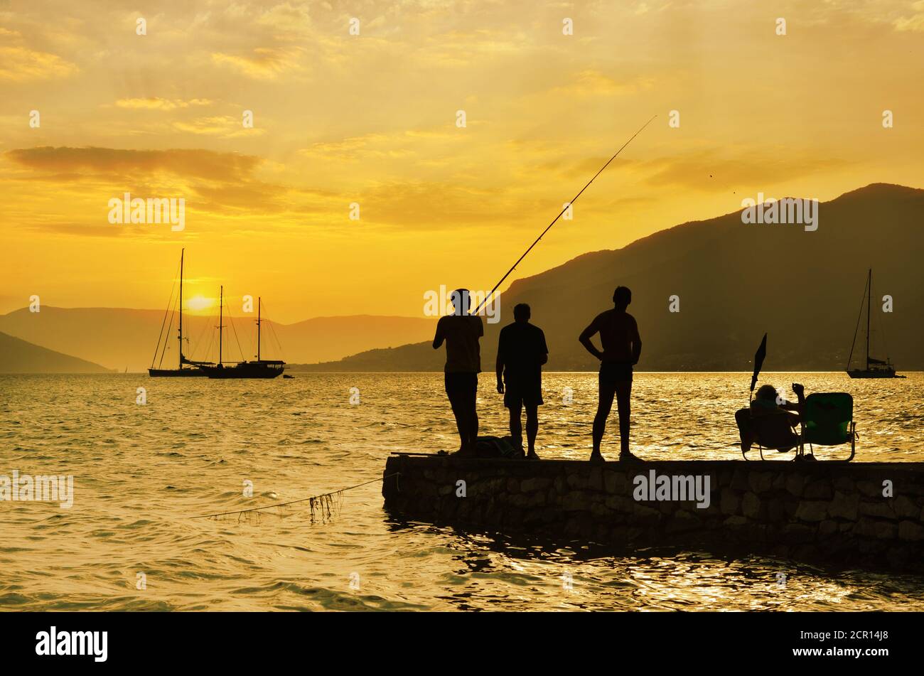 Menschen genießen das Leben am Meer, Freizeit, Angeln und lässig hängen mit Freunden, entspannte Leute bei Sonnenuntergang Med Stil Stockfoto