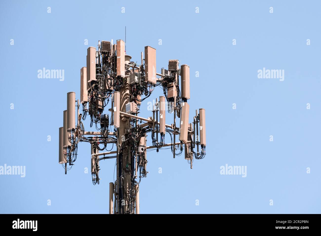 Nahaufnahme des Mobilfunkmastes mit Antennen für drahtlose Kommunikation; blauer Himmel und Kopierfläche rechts Stockfoto