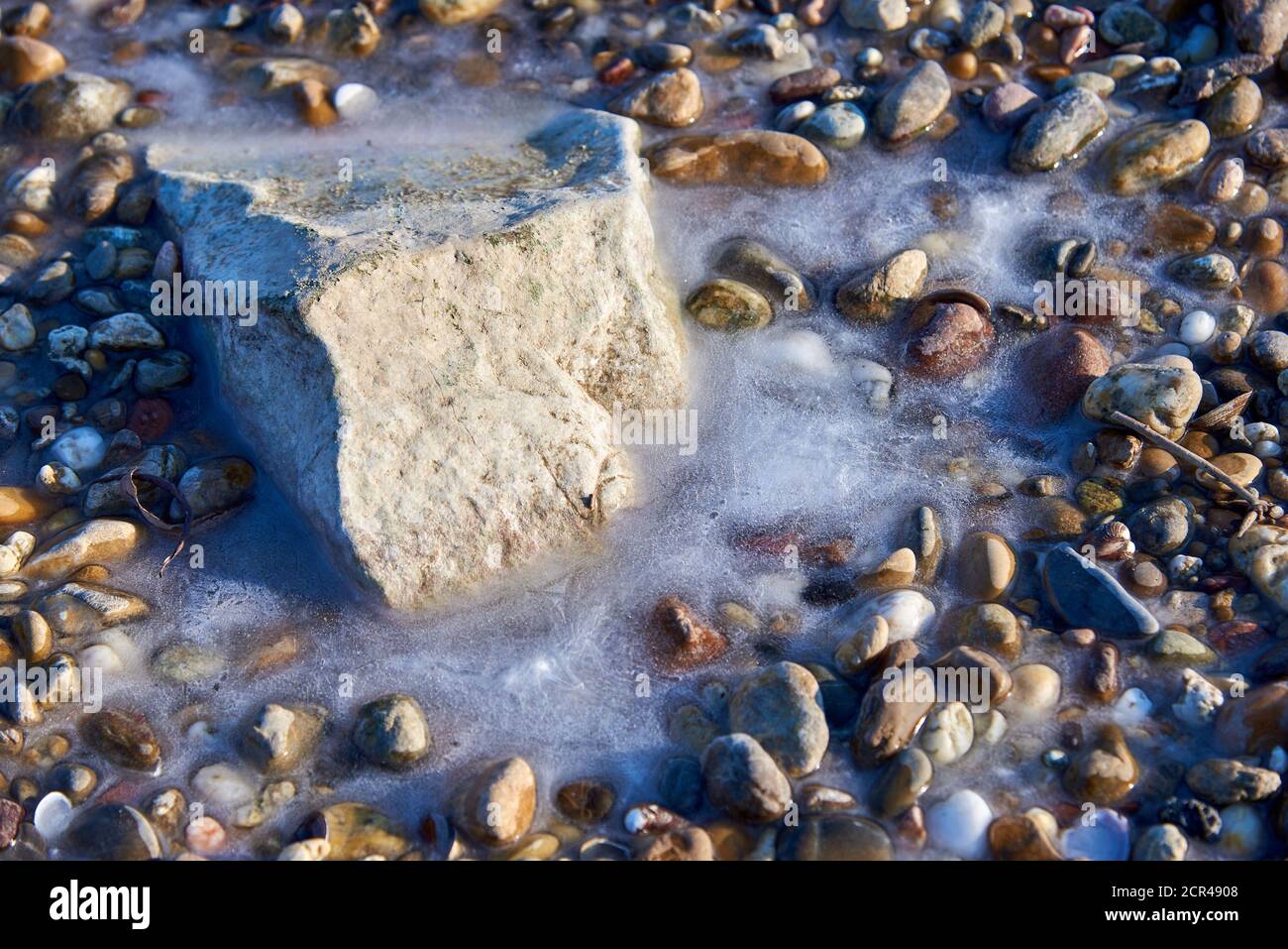 Felsen und Kieselsteine im Wasser gefroren Stockfoto