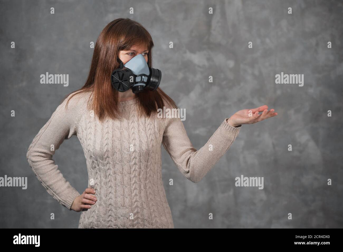 Mädchen in Atemschutzmaske hielt ihre Hand zur Seite und zeigte auf den Kopierraum. Epidemie und Gesundheitskonzept. Stockfoto Mädchen in Atemschutzmaske hielt ihre Hand zur Seite und zeigte auf den Kopierraum. Epidemie und Gesundheitskonzept. Stockfoto