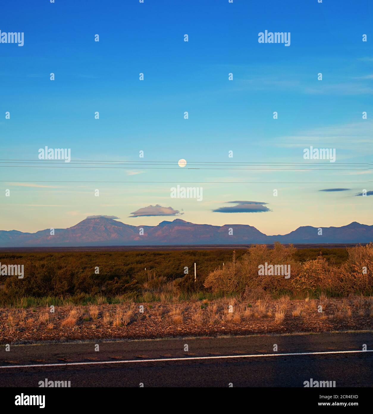 Am frühen Morgen Licht auf südwestlichen Wüstenlandschaft, mit Straße, Gras, Wüste-Gestrüpp, Berge, Wolken, und am frühen Morgen, wie es in den Himmel untergeht. Stockfoto