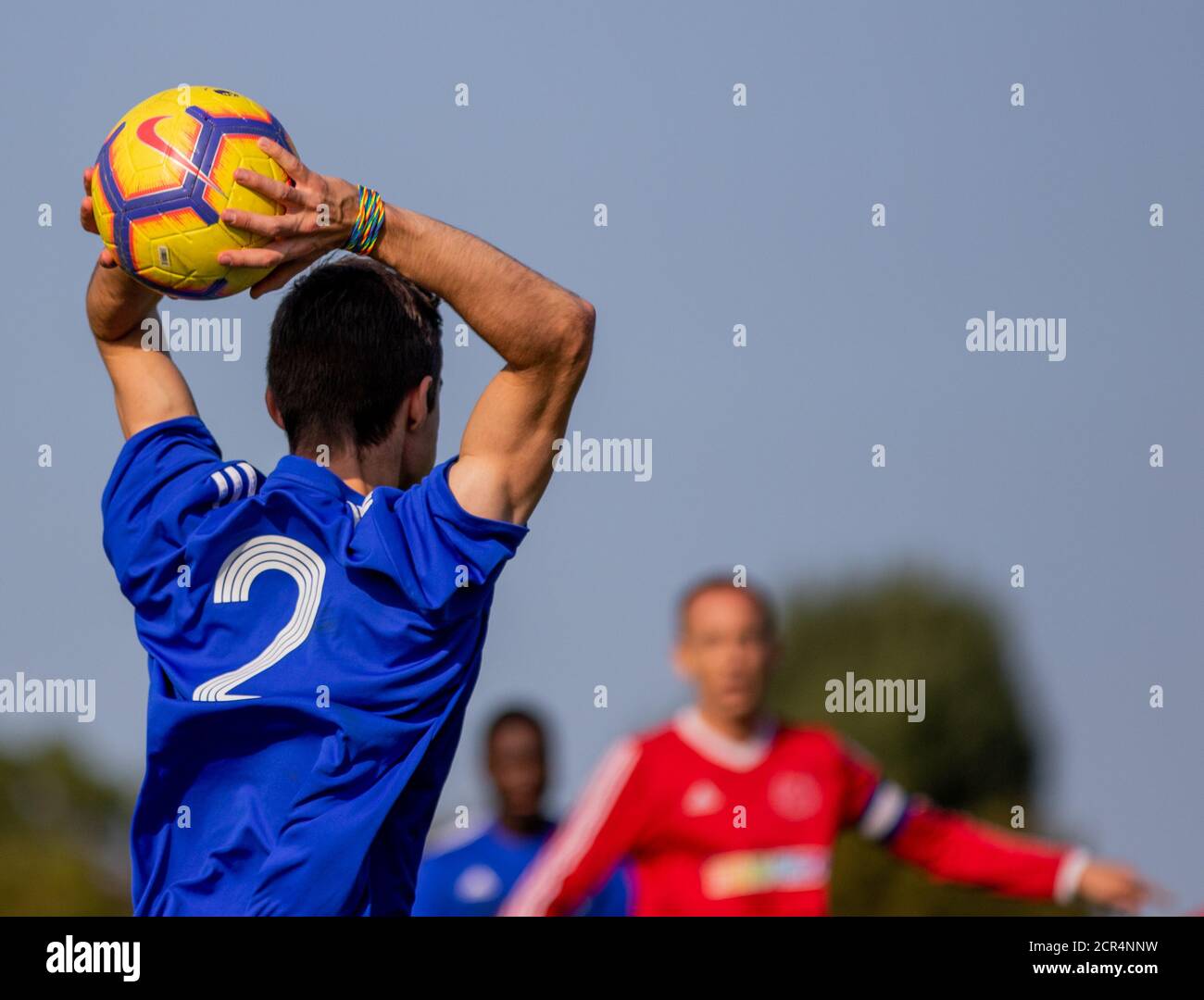 Fußballer in Blau trägt Regenbogen Armbinde einen Wurf in. Stockfoto