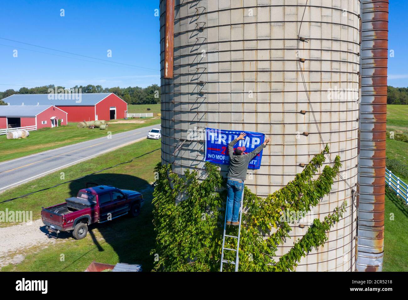 Middleville, Michigan, USA. September 2020. Broc Reaser hängt ein Trump-Banner auf dem Silo des Bauern John Seeber. Seeber sagte, er wolle das Banner hoch auf dem Silo, weil jemand mehrere seiner Trumpf-Rasenschilder gestohlen habe. Kredit: Jim West/Alamy Live Nachrichten Stockfoto
