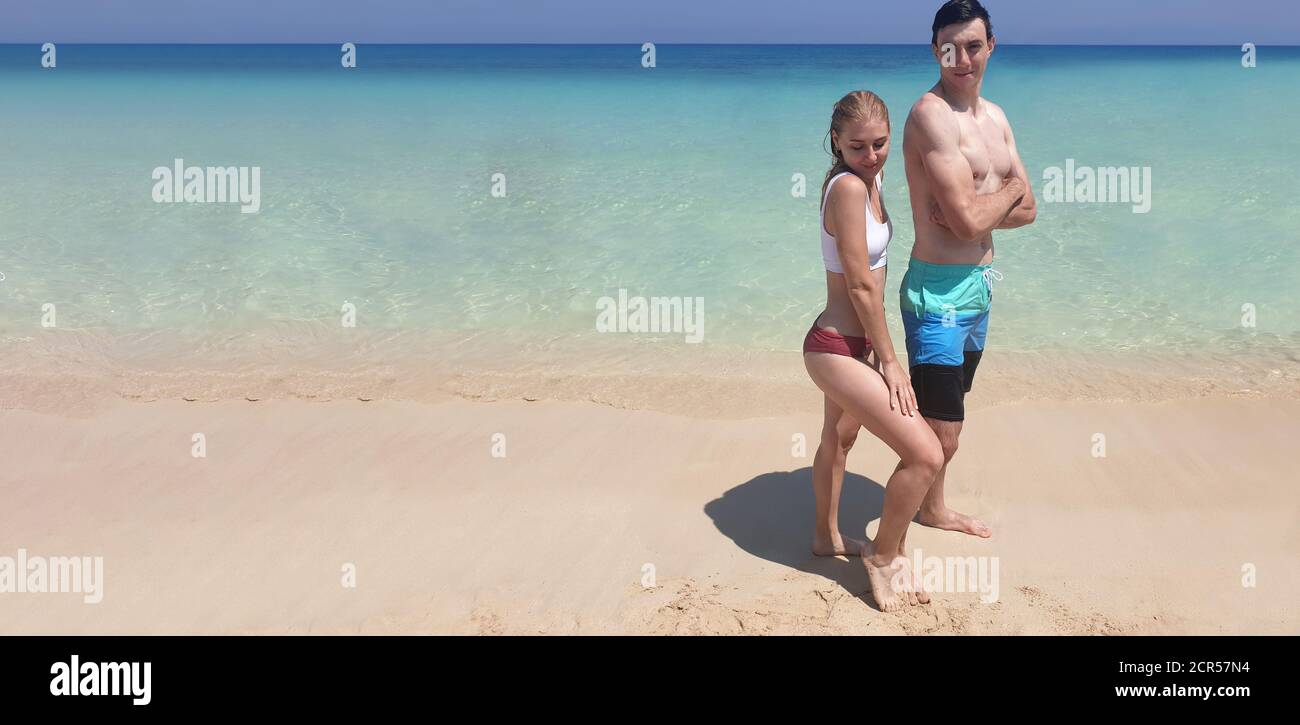 Reisen und ausruhen. Junge Erwachsene Mann und Frau posieren vor dem Hintergrund der reinen blauen Meer auf Sand, Banner Stockfoto