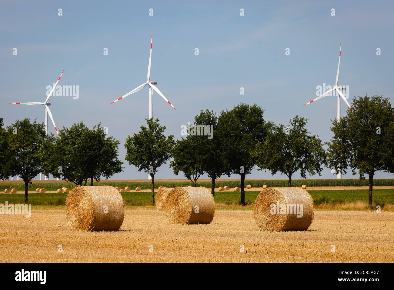 Linnich, Nordrhein-Westfalen, Deutschland - nach der Getreideernte liegen Strohballen auf dem Stoppelfeld, hinter Windkraftanlagen im Windpark. Stockfoto