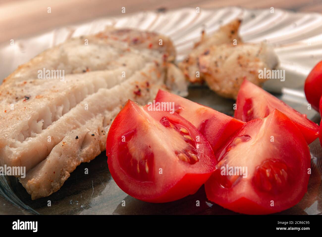Leckere Tomatenstücke mit Fisch und Gewürzen zum Abendessen serviert Stockfoto