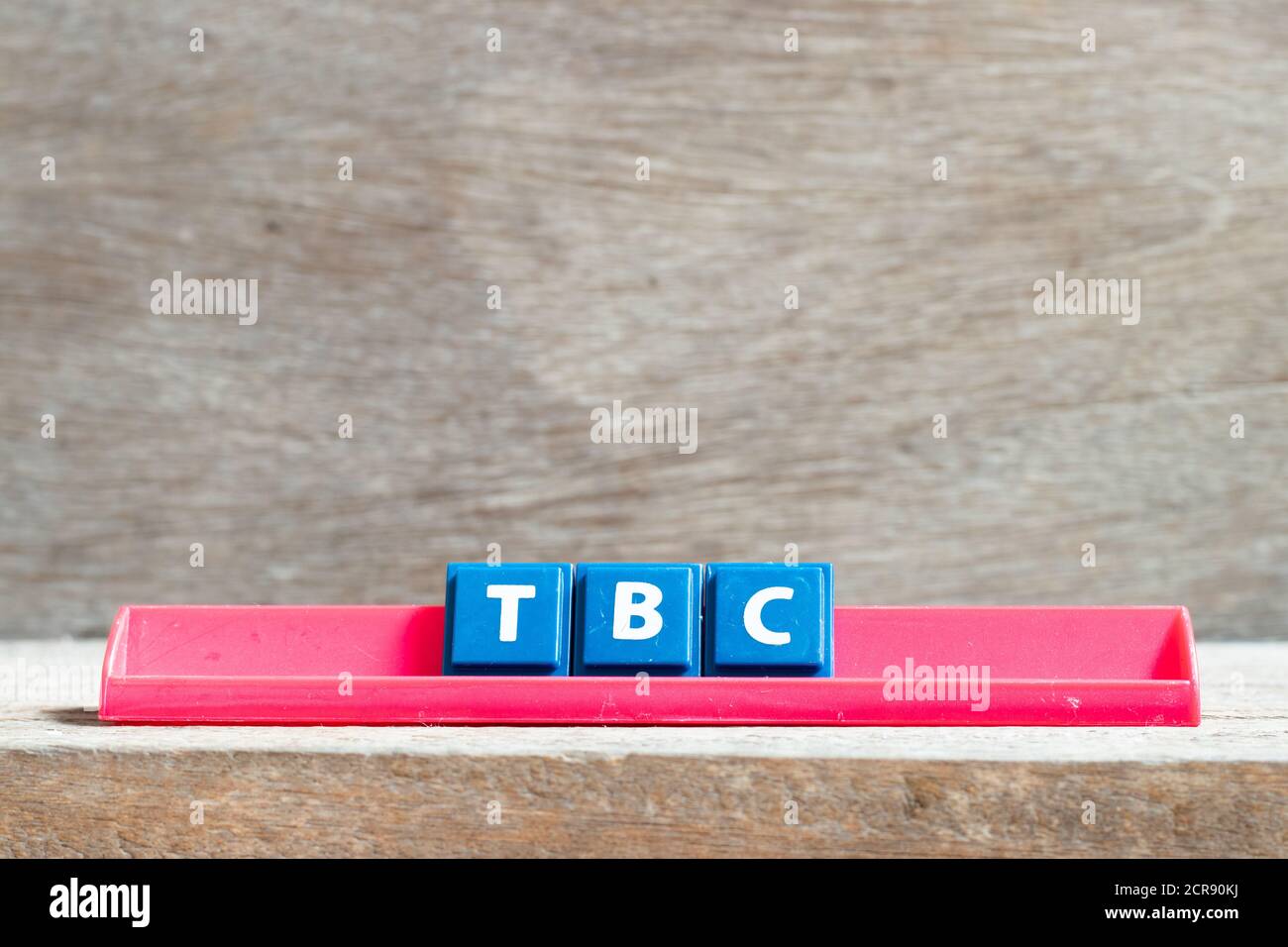 Kachelbuchstabe auf rotem Gestell in Wort TBC (Abkürzung von muss bestätigt oder fortgesetzt werden) auf Holzhintergrund Stockfoto