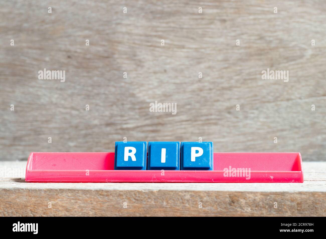 Anordnen des Buchstabens auf dem roten Gestell im Wort RIP (Abkürzung für Ruhe in Frieden) auf Holzgrund Stockfoto