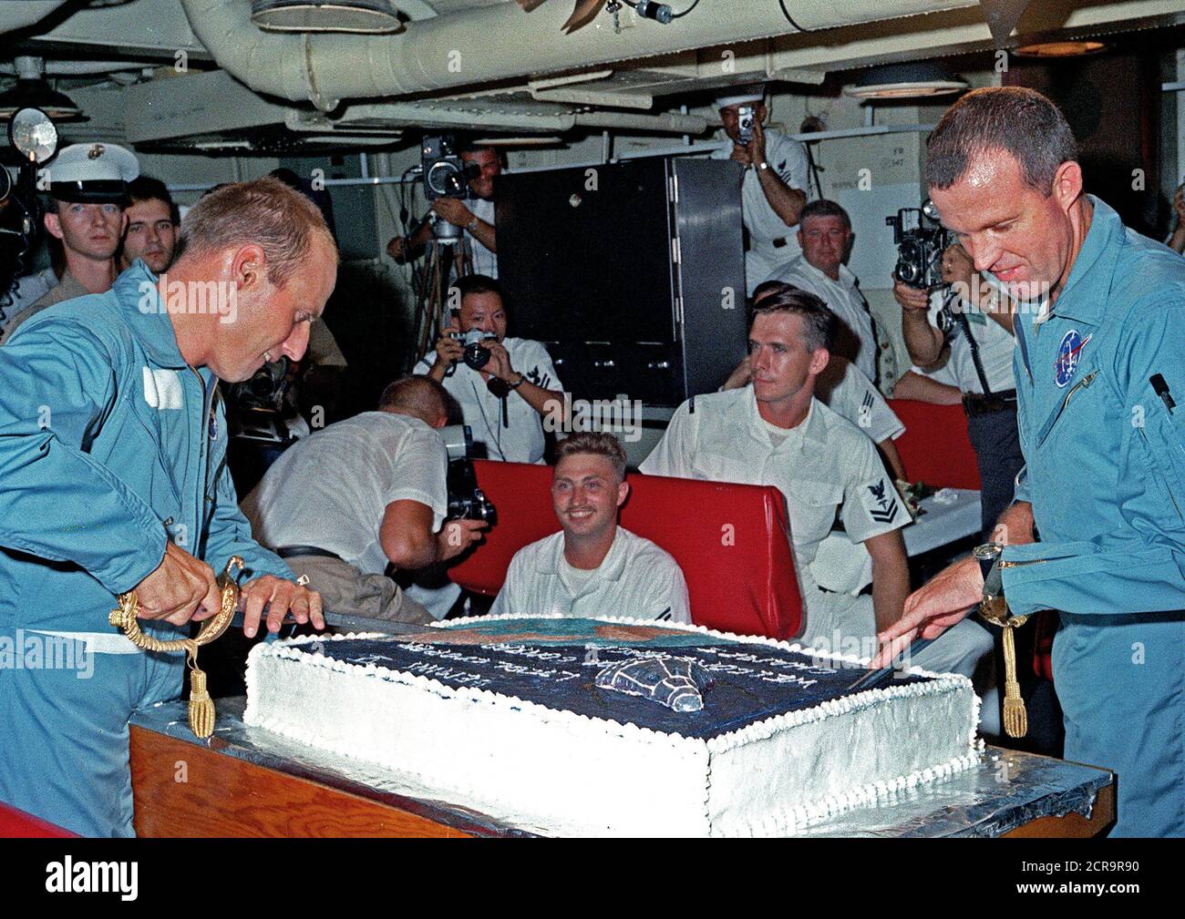 Astronauten Charles Conrad Jr (links) und L. Gordon Cooper jr. Vorbereitung für die Schicht in der riesigen Kuchen für Sie von den Köchen zubereitet an Bord der Flugzeugträger USS Lake Champlain. Stockfoto
