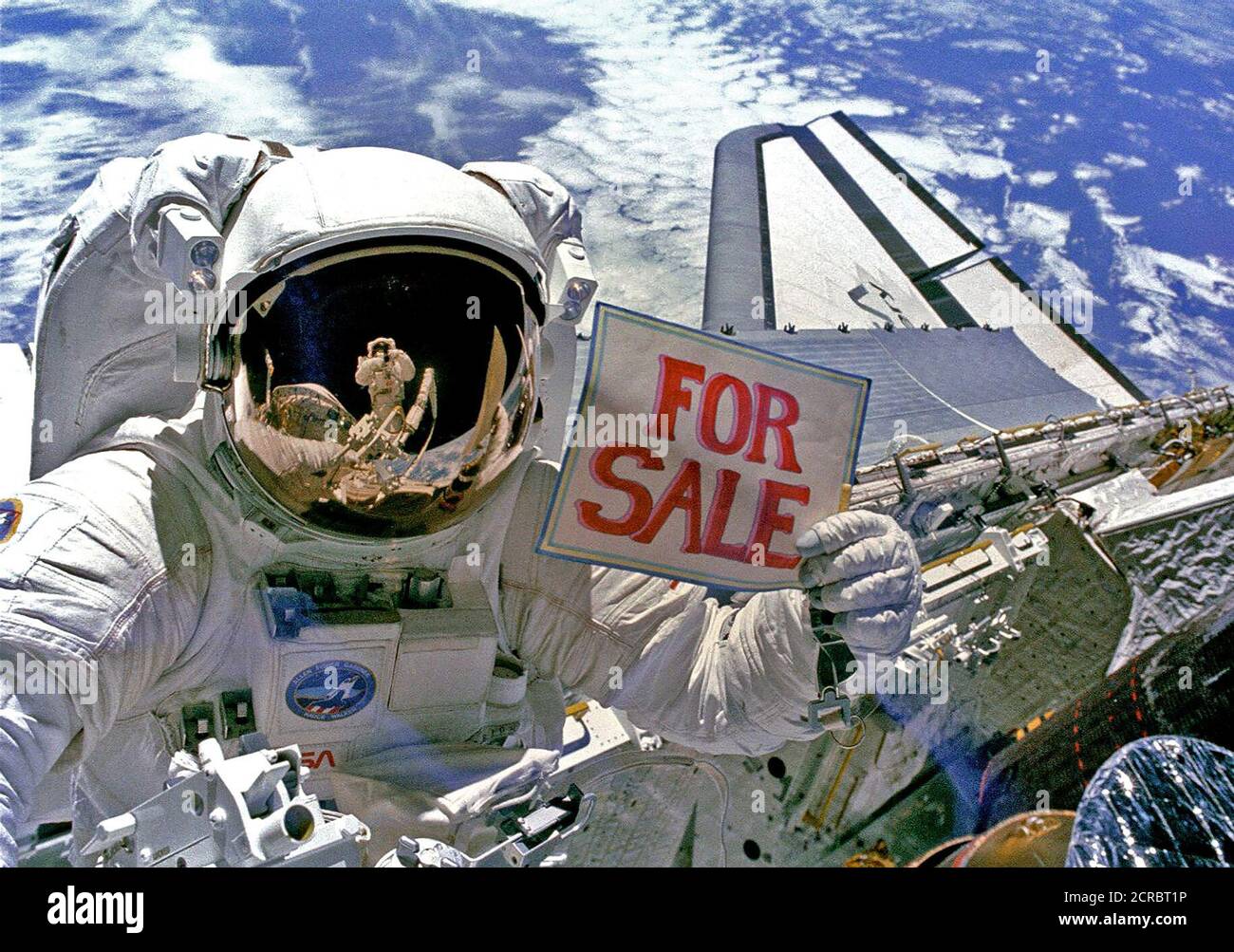Astronaut Dale A. Gardner, der gerade den größten Teil seines zweiten Extra Vehicular Activity (EVA) Zeitraum in drei Tagen, hält ein Schild "Zum Verkauf" bezieht sich auf die beiden Satelliten, Stockfoto