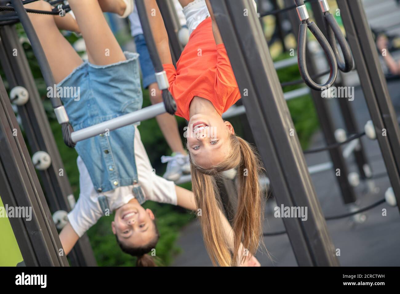 Mädchen hängen mit dem Kopf nach unten auf dem Spielplatz Stockfoto