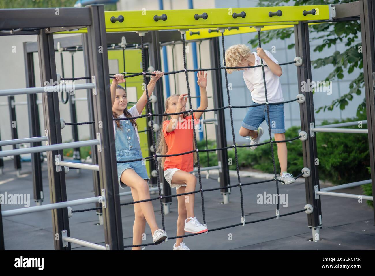 Kinder klettern auf Spielplatz im Freien und schauen aufgeregt Stockfoto