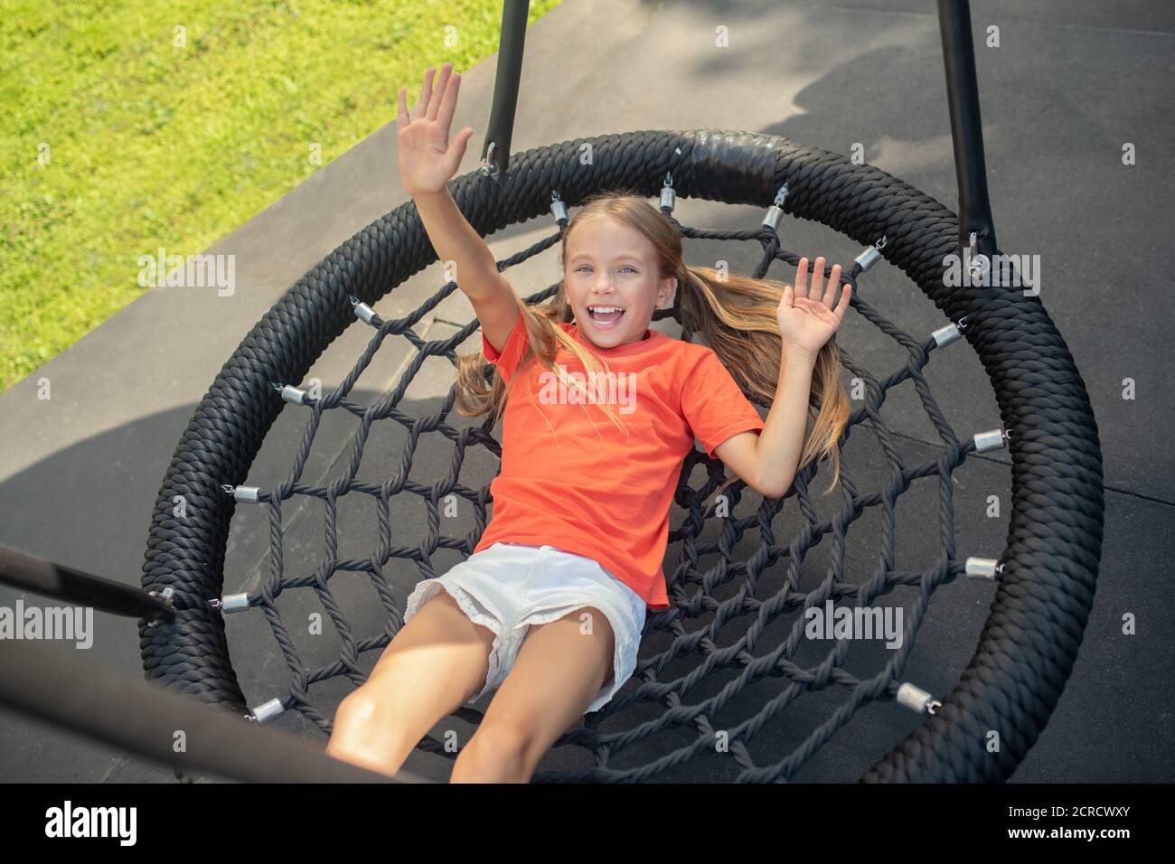 Mädchen ruht sich nach dem Spiel aus und winkt mit der Hand Stockfoto