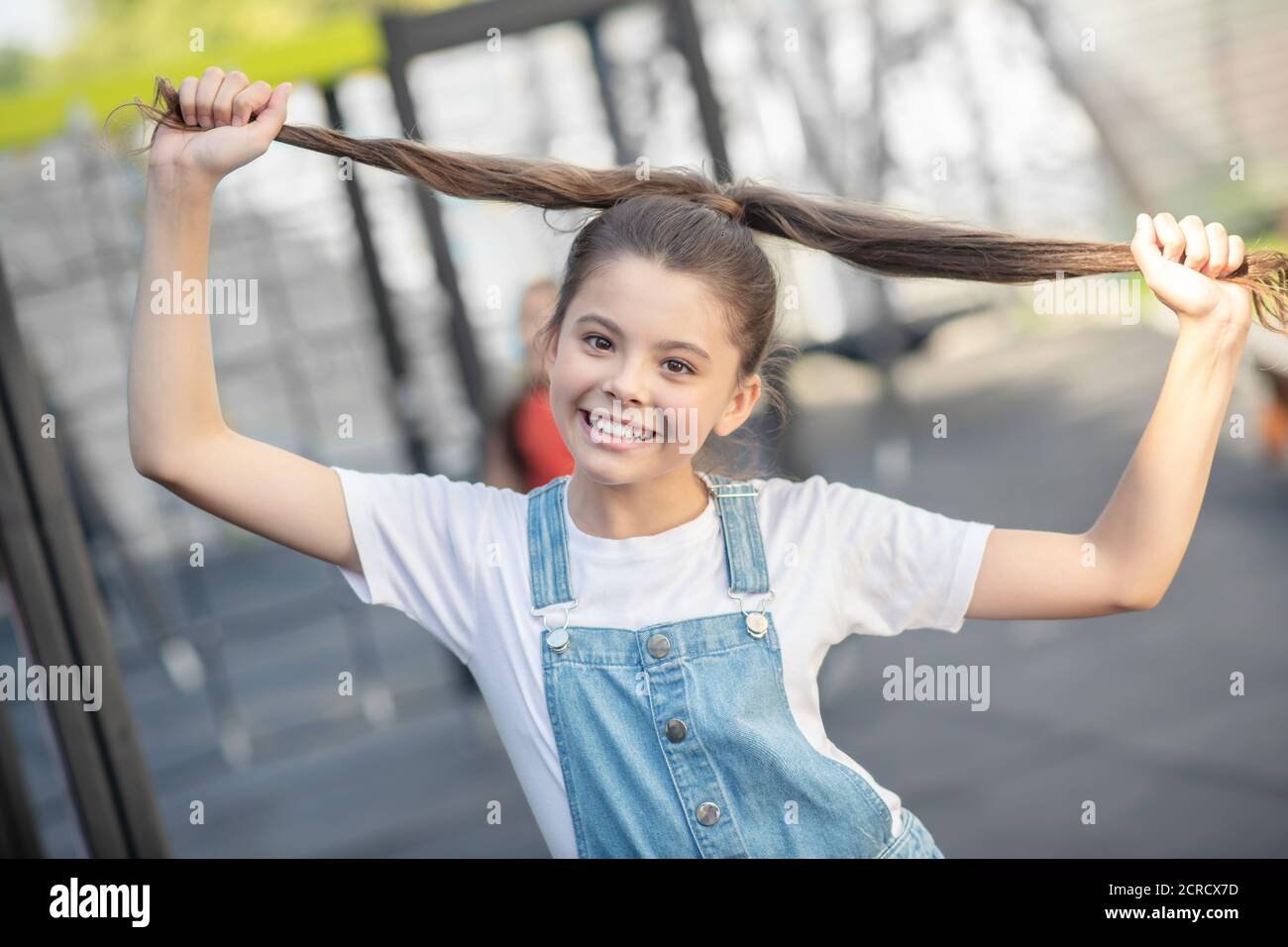 Nettes Mädchen hält ihr Haar und Stretching es zu den Seiten Stockfoto