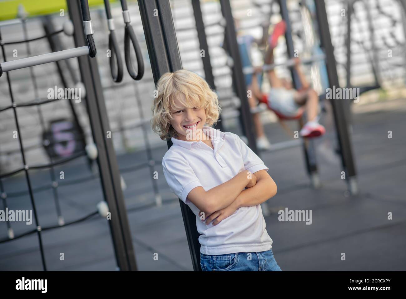Blonde junge in weißem T-Shirt stehen mit gekreuzten Armen Stockfoto