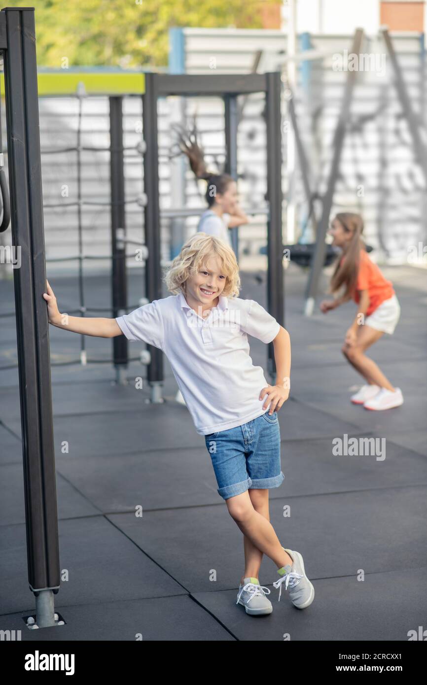Blonde junge in weißen T-Shirt stehen und lächeln Stockfoto