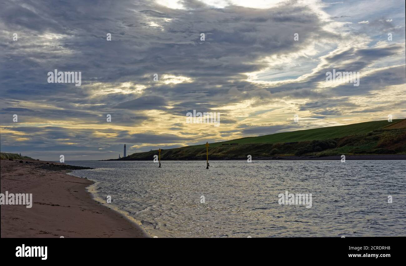 High Tide am Montrose Harbour, mit den Navigation Markers und Scurdie Ness in der Ferne unter einem gelb getönten wolkigen Himmel bei Sonnenaufgang. Stockfoto