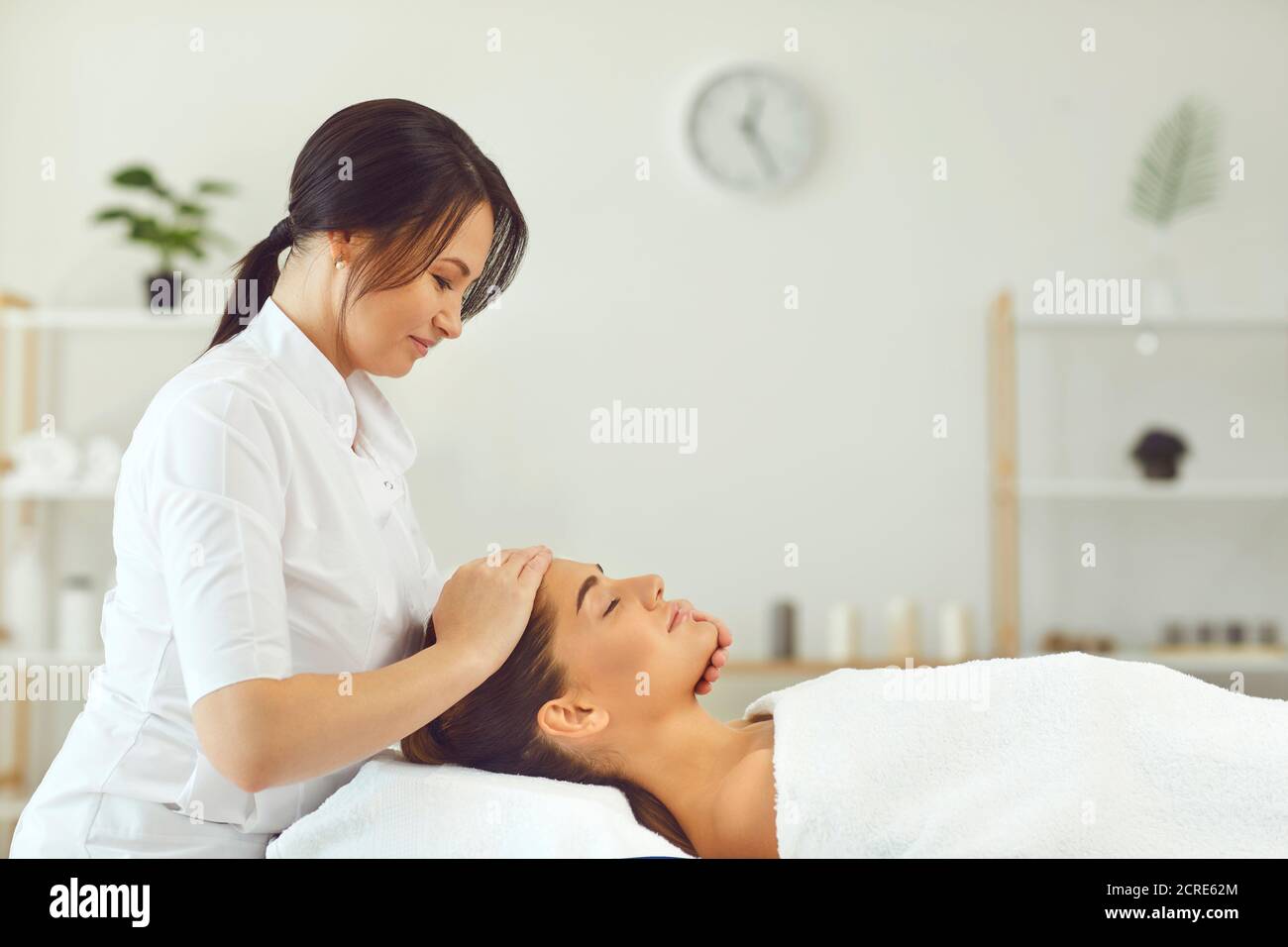 Lächelnde Frau Dermatologe macht professionelle manuelle entspannende Massage für junge Frau Stockfoto