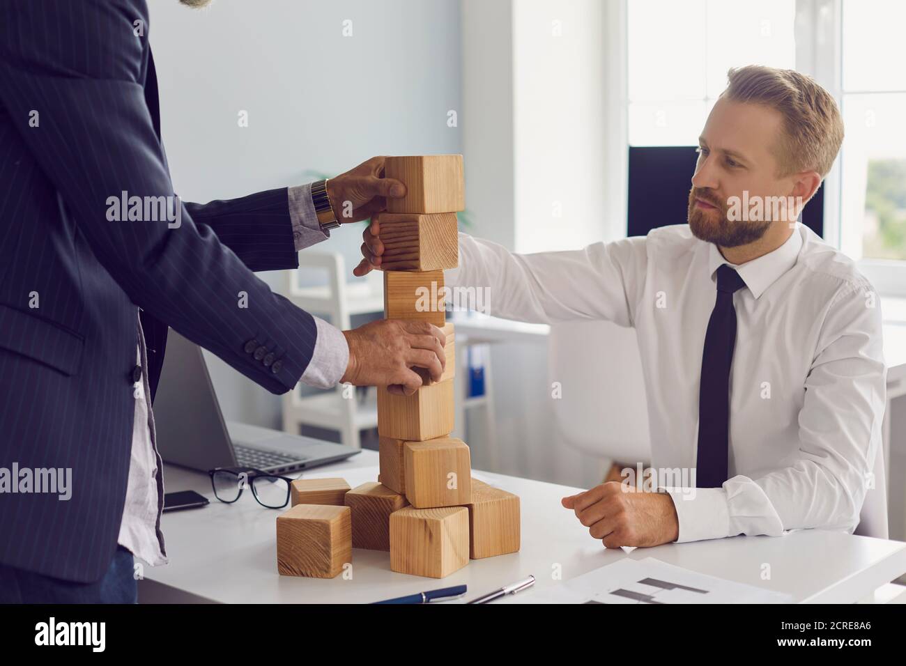 Partner bauen Turm aus Holzblöcken auf Bürotisch gemeinsam entwickeln Strategie für Unternehmen. Stockfoto