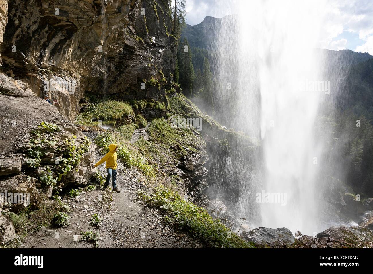 Junge in gelber Jacke auf Trail unter dem schönen Wasserfall Johanneswasserfall, Obertauern, Österreich Stockfoto