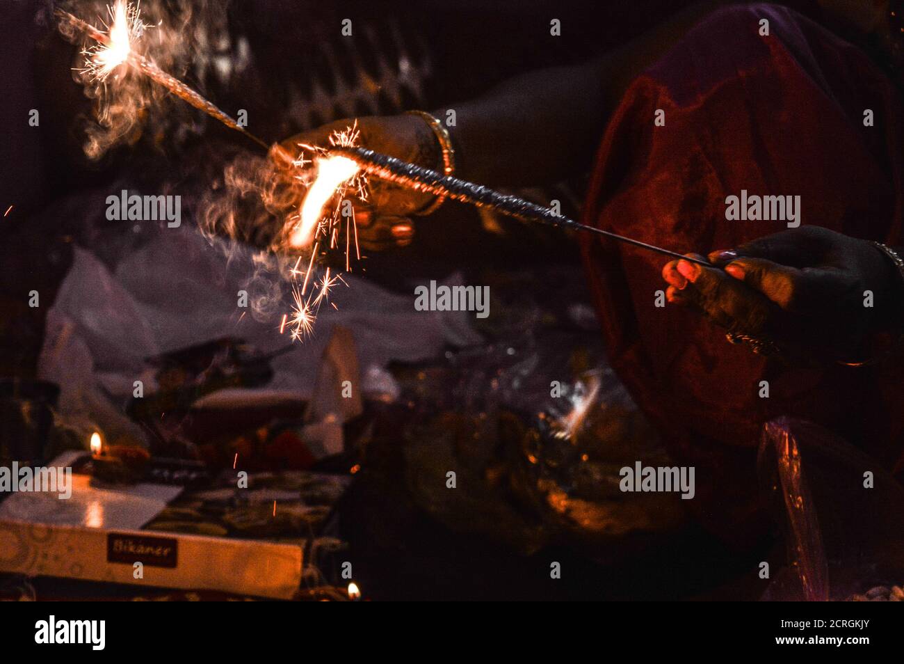 Indische Dame Spielen mit Feuer Cracker mit Rose und Kerze auf indischen Festival diwali deepawali mit Feuer am Tisch isoliert Stockfoto