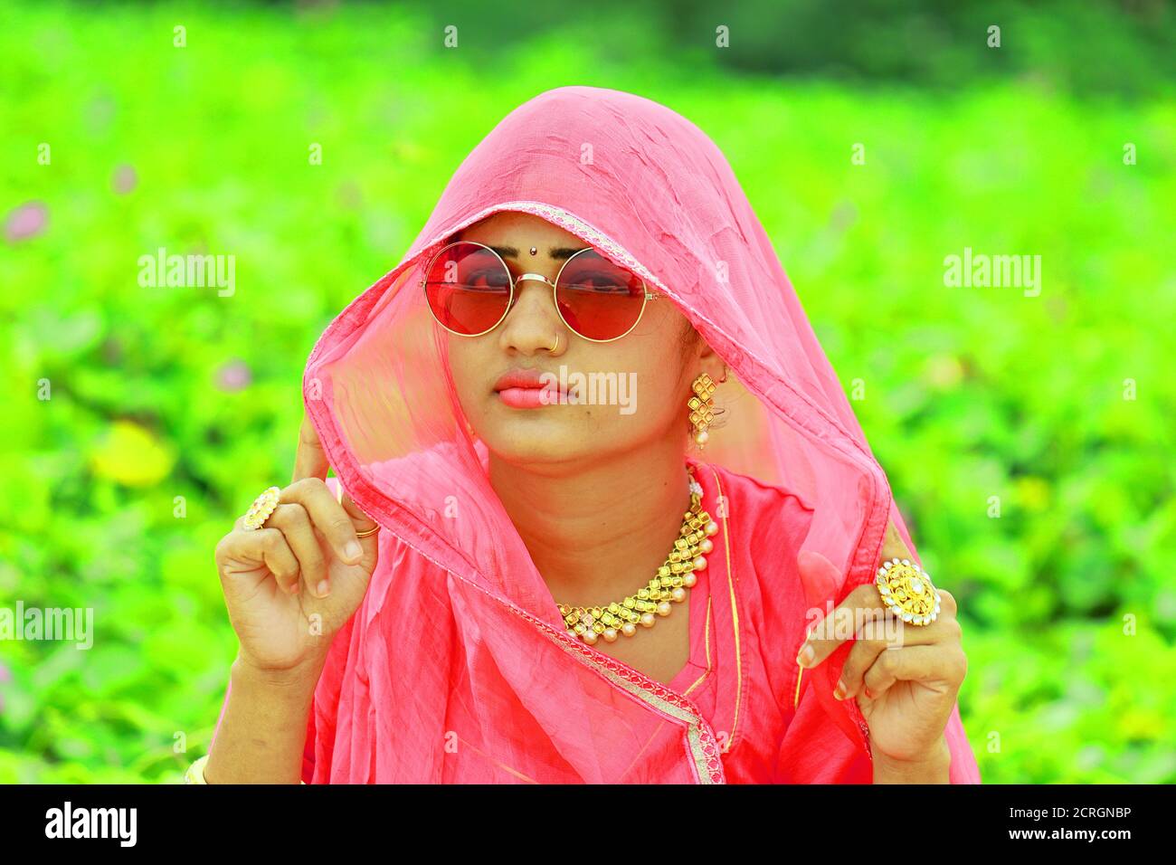 Ein Nahaufnahme Porträt Bild von indischen schönen jungen Frau Gesicht Mit tragen rosa farbigen traditionellen Rajasthani rajputi Kleid und glänzend Elegante Brille Stockfoto