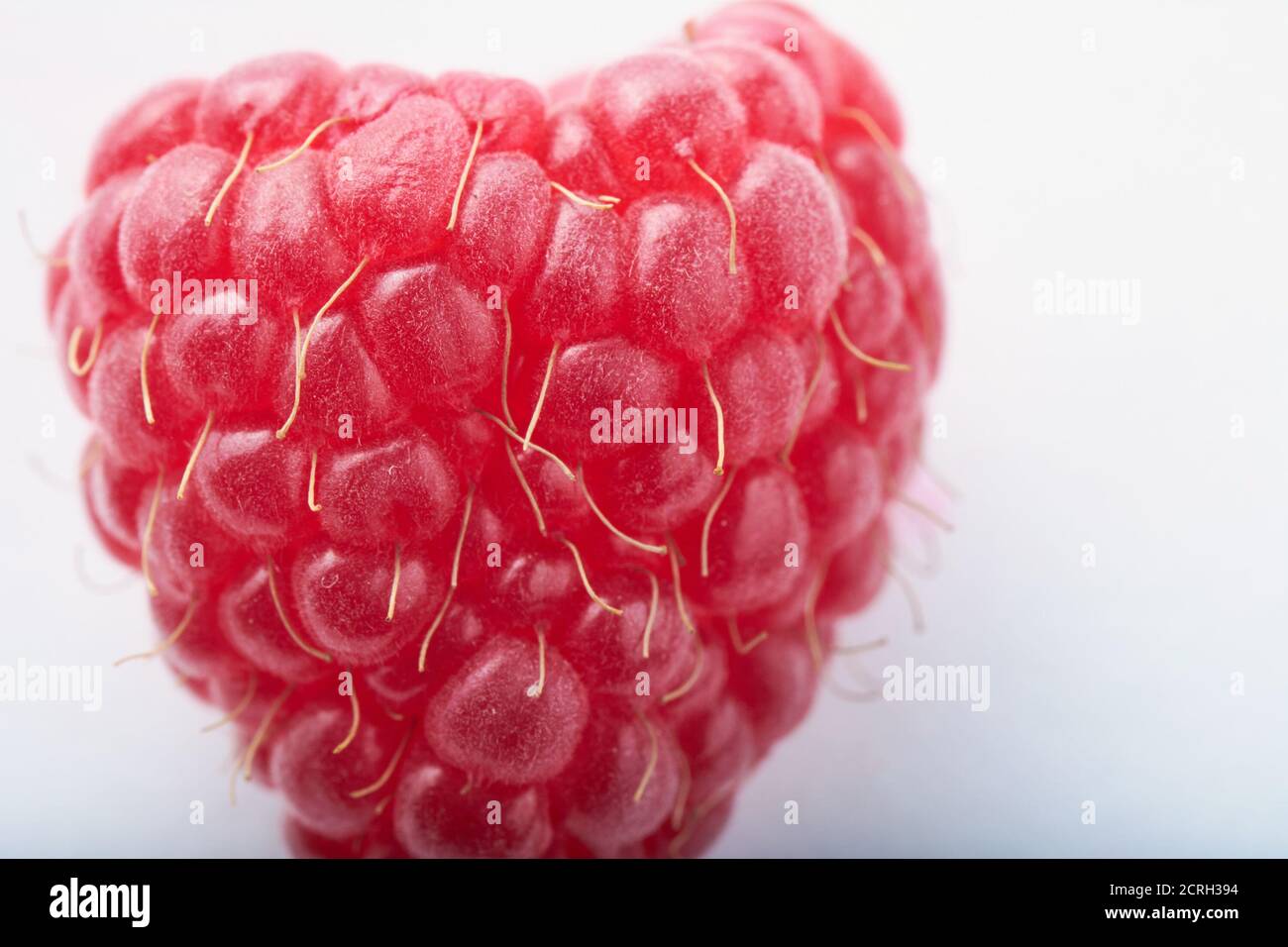 Himbeeren in Form von Herz auf weißem Hintergrund. Makrofoto. Draufsicht Stockfoto