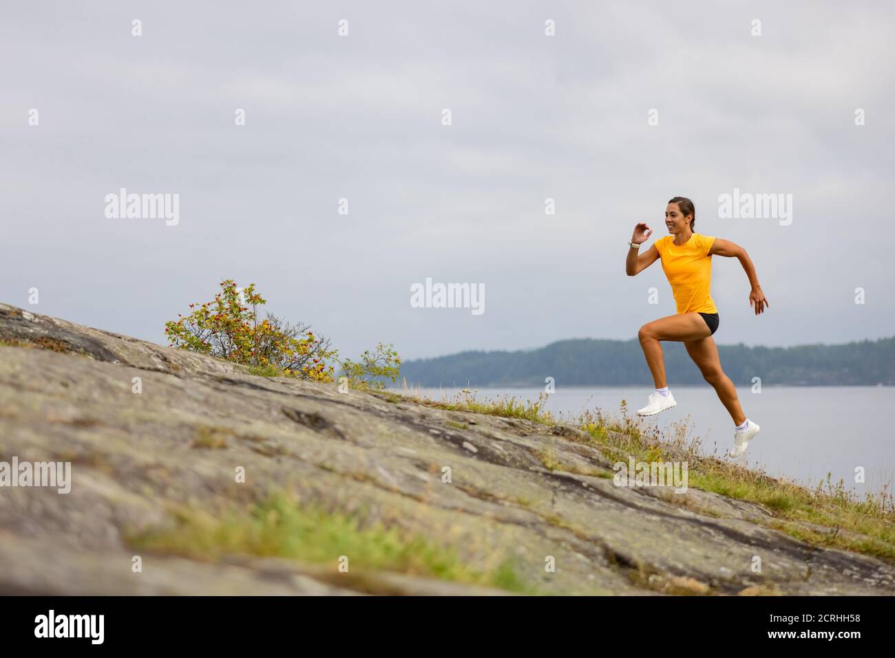 Seitenansicht der Fitness-Frau beim hochintensiven Laufen am Berghang Am Meer Stockfoto