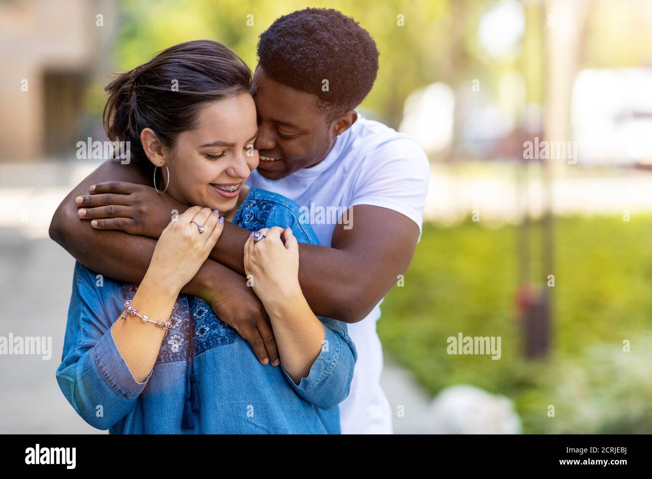 Liebevolles multiethnisches Paar umarmt im Freien Stockfoto