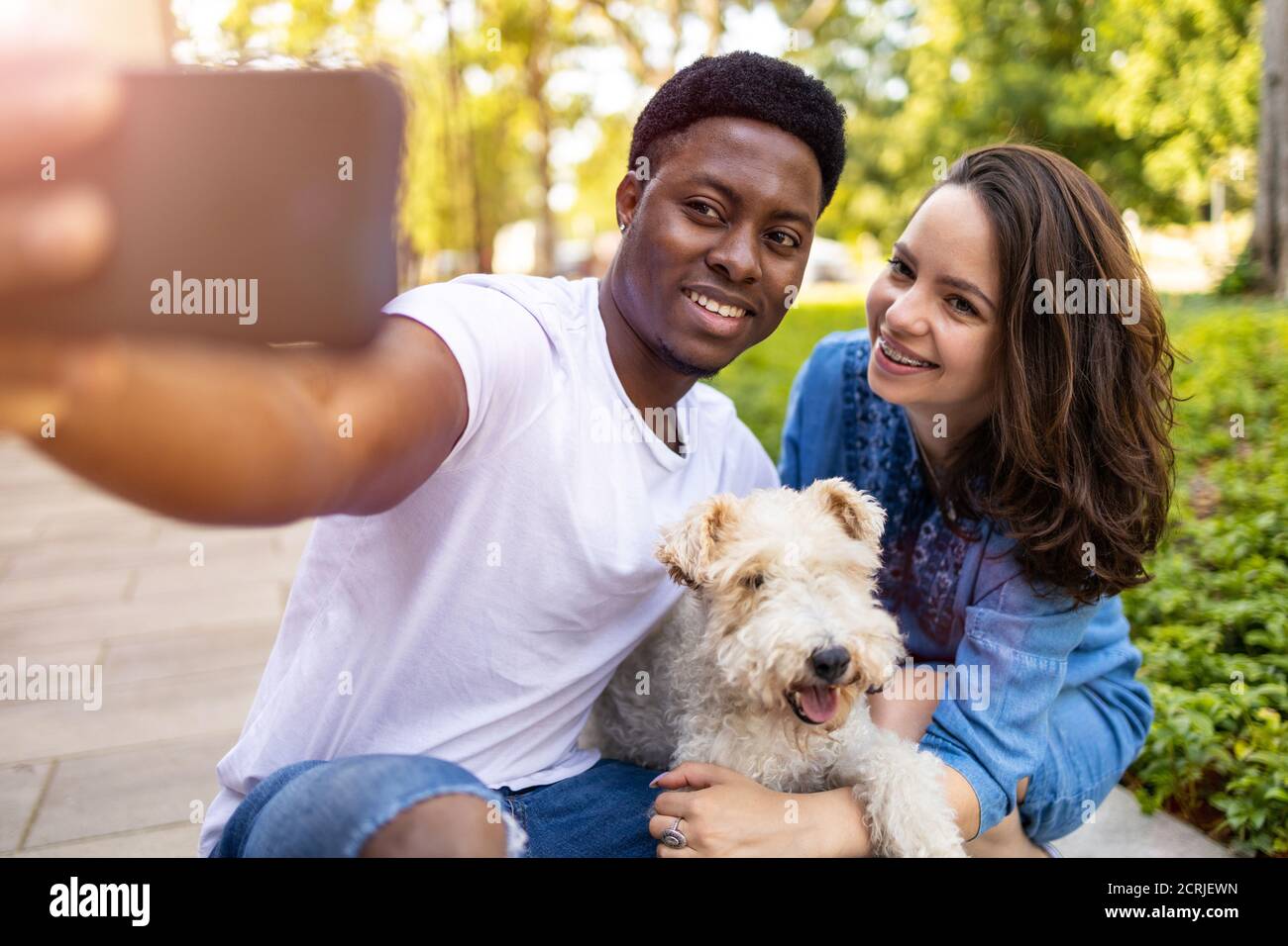 Glückliches junges Paar mit ihrem Haustier Hund im Freien Stockfoto