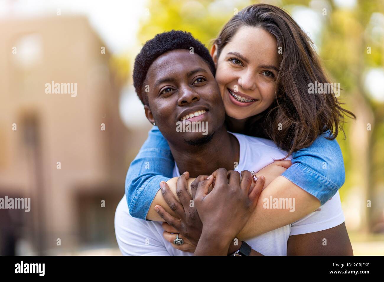 Liebevolles multiethnisches Paar umarmt im Freien Stockfoto