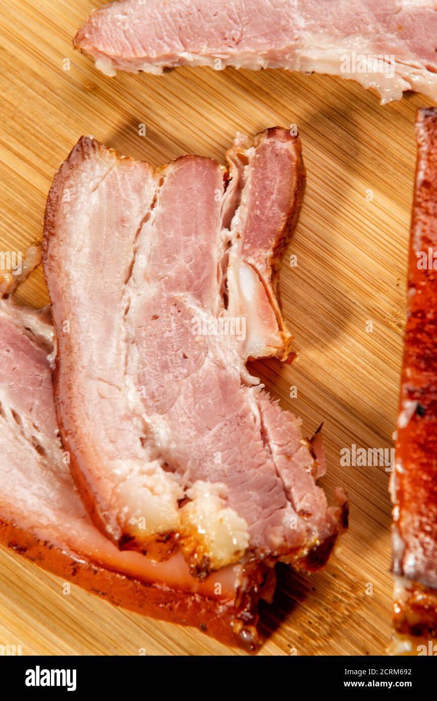 In Scheiben geschnittenes geräuchertes Fleisch liegt auf einem Holztisch Stockfoto